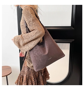 Detail of deep brown large tote bag in soft matte leather with brand logo accent