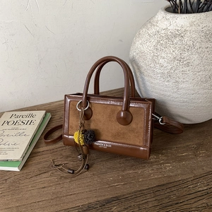 Detailansicht der braunen Vintage-Tasche aus Leder und Wildleder mit dekorativem Pompon