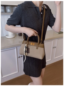 Détail du sac seau en toile avec bandoulière en cuir brun et breloque chocolat en cuisine