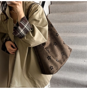 Detailed macro view of laser-cut floral patterns on vintage brown suede hobo tote bag
