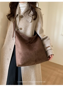Detailed close-up of a large brown suede hobo bag worn with a chic winter wool coat