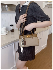 Détail du sac seau élégant avec fermoir rotatif en métal et pendentif chocolat