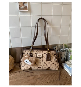 Close-up of light brown tote bag with bear print and decorative plush bear charm