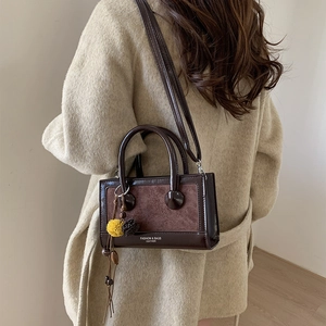 Detailansicht der braunen Umhängetasche aus Leder mit Wildlederflicken und gelber Quaste