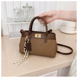 Detailed view of brown bucket bag with canvas leather mix and gold twist lock clasp