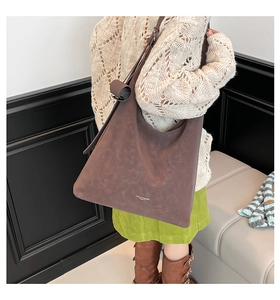 Close-up of deep brown tote bag with suede texture and shoulder strap on model
