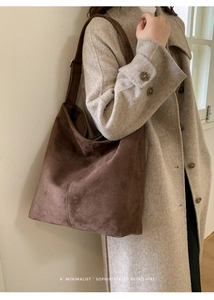 Detail of a dark brown suede tote bag on a model wearing an oatmeal wool coat
