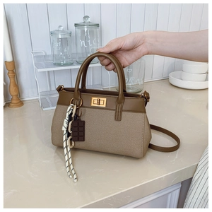 Detail of khaki canvas bucket bag with brown leather trim and vintage gold clasp