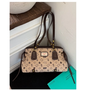 Detail of vintage beige suede tote bag featuring cat patterns and brand label on white wood