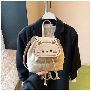 Détail d'un sac à dos chat beige avec oreilles brodées et texture mate élégante