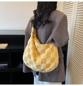 Detailed close-up of a yellow plush checkered tote bag with golden zipper on model