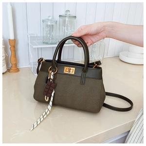 Detail of dark green canvas bucket bag with leather trim and chocolate pendant charm