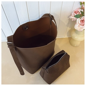 Detail of dark brown vintage bucket bag with matching pouch on a floral background