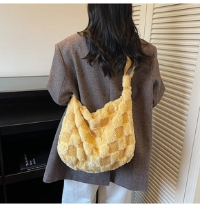 Detail view of large yellow plush checkered tote bag worn on shoulder by a model