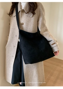 Close-up of minimalist black matte suede shoulder bag with wide strap for winter