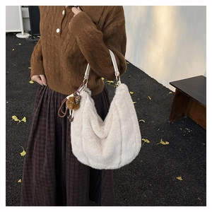 Gros plan sur un sac hobo en peluche blanche avec bandoulière et pendentif en décor d'automne