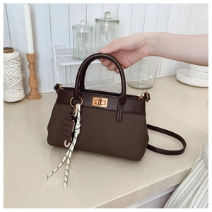 Detail of dark coffee bucket bag featuring golden twist lock and textured fabric finish