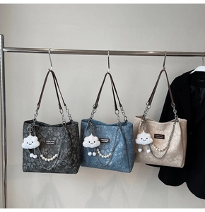 Detailed view of floral textured shoulder bags with pearl chains and cloud charms