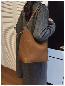 Brown leather bucket bag styled with a grey coat for a minimalist autumn winter look