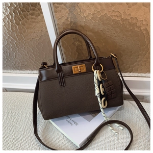 Détail d'un sac à main marron foncé vintage avec fermoir doré et breloque décorative