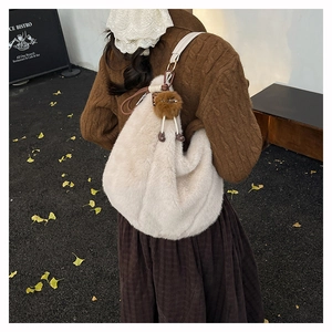 Vue détaillée du sac bandoulière en fausse fourrure blanche avec charm sur un mannequin