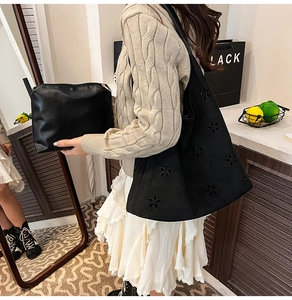 Detail of black suede tote bag with hollow flower cutout design and matching inner pouch