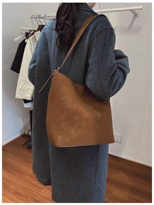 Brown leather bucket bag shown on shoulder from side view for size and fit reference