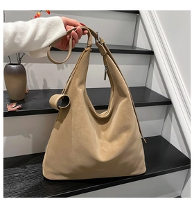 Detail of a khaki tote bag with soft pleated texture and adjustable strap on a staircase