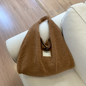 Detail of caramel faux shearling tote bag featuring a SEEYOU label and soft teddy texture