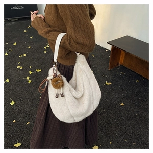 Détail du sac hobo en fausse fourrure blanche avec bandoulière et breloque peluche en automne