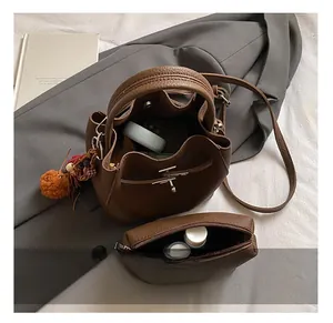 Dettaglio borsa a secchiello marrone in pelle litchi con pochette interna e pompon morbido