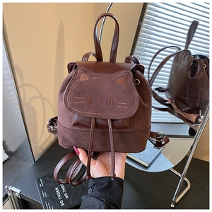 Détail d'un mini sac à dos en daim marron avec broderie chat et fermeture à cordon