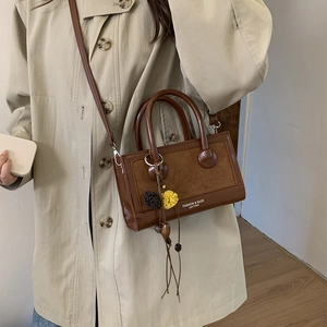 Nahaufnahme der braunen Patchwork-Tasche mit Anhängern und mattierter Lederstruktur