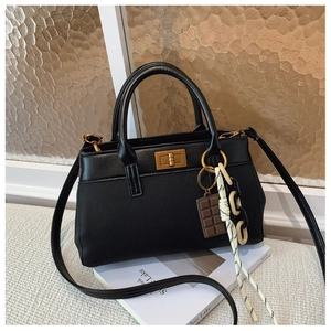 Détail du sac seau noir en cuir PU avec fermoir doré et breloques décoratives