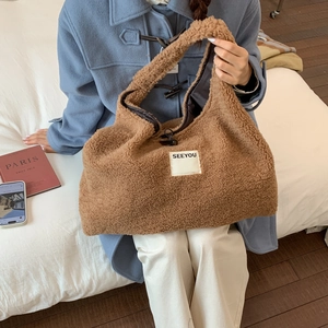 Detail of dark brown faux shearling tote bag with SEEYOU label and zip closure