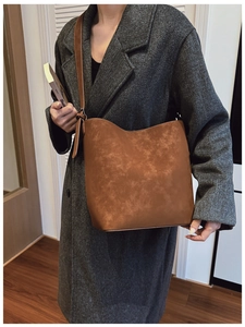 Detail of vintage brown bucket bag showing the unique aged leather texture and wide strap