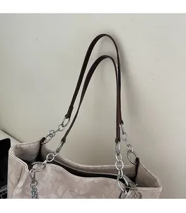 Detail of cream shoulder bag featuring jacquard floral texture and brown leather strap
