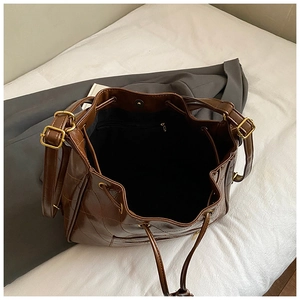 Detail view of large dark brown quilted bucket bag with gold hardware and spacious interior