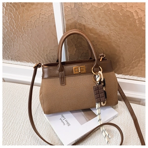 Détail du sac seau en toile avec bordure en cuir, fermoir doré et pendentif chocolat