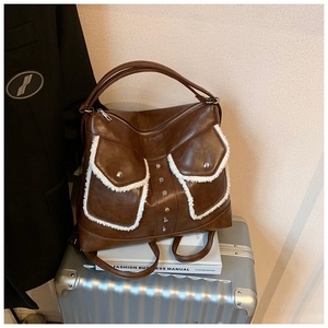 Detail view of brown leather tote bag with white fleece trim and metal rivet accents