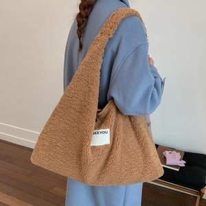 Detail view of brown faux shearling tote bag with SEEYOU label on a blue coat