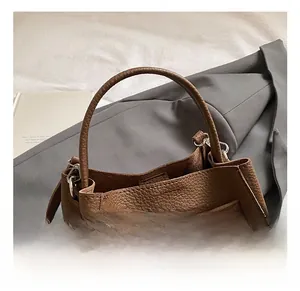 Dettaglio della borsa a secchiello in pelle litchi marrone scuro con fibbia in metallo