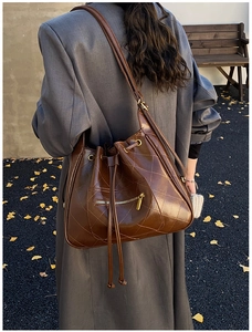 Detail of a dark brown quilted bucket bag with drawstring and polished leather finish
