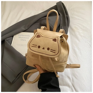 Détail de la broderie chat et du mélange de textures sur un mini sac à dos beige