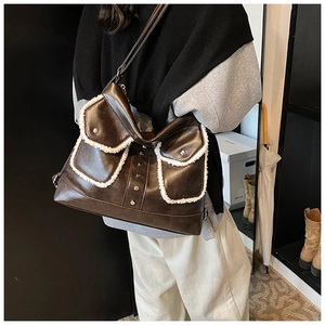 Close-up of brown faux leather tote with white shearling trim and silver metal rivets