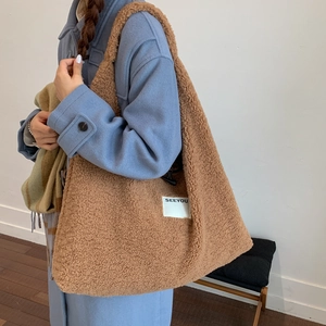 Detail of a large brown faux fur tote bag with SEEYOU label on a shoulder strap