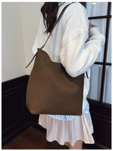Brown bucket shoulder bag detail with matte texture and minimalist half-moon shape