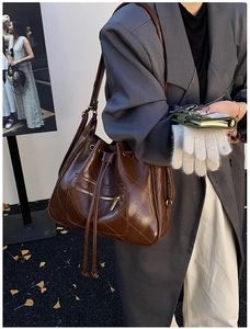 Detail of dark brown quilted leather bucket backpack with gold zipper and drawstring closure