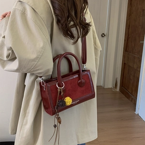 Detailansicht einer dunkelroten Tasche aus glänzendem Leder und mattem Wildleder-Mix