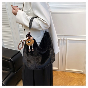 Détail du sac hobo en fausse fourrure noire avec anse en cuir et pendentif en peluche